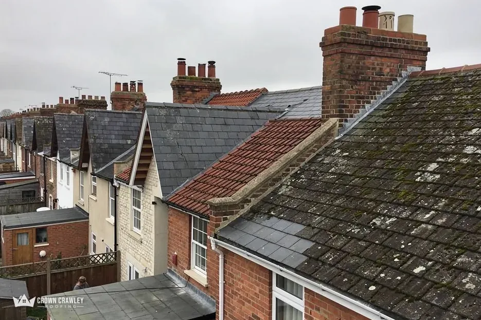 Chimney stack on a mossy tiled roof among terraced houses