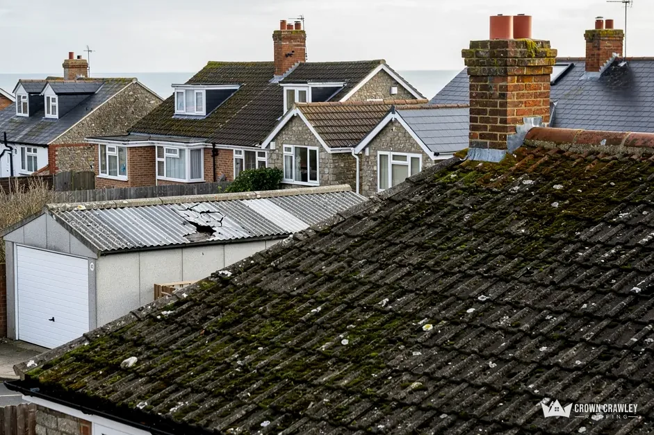 Moss-covered tiled roof sloping down towards garages