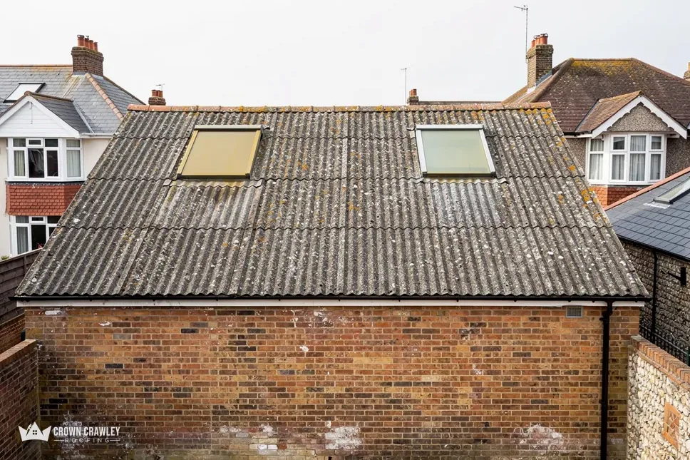 Corrugated cement garage roof with two rooflights above a brick wall