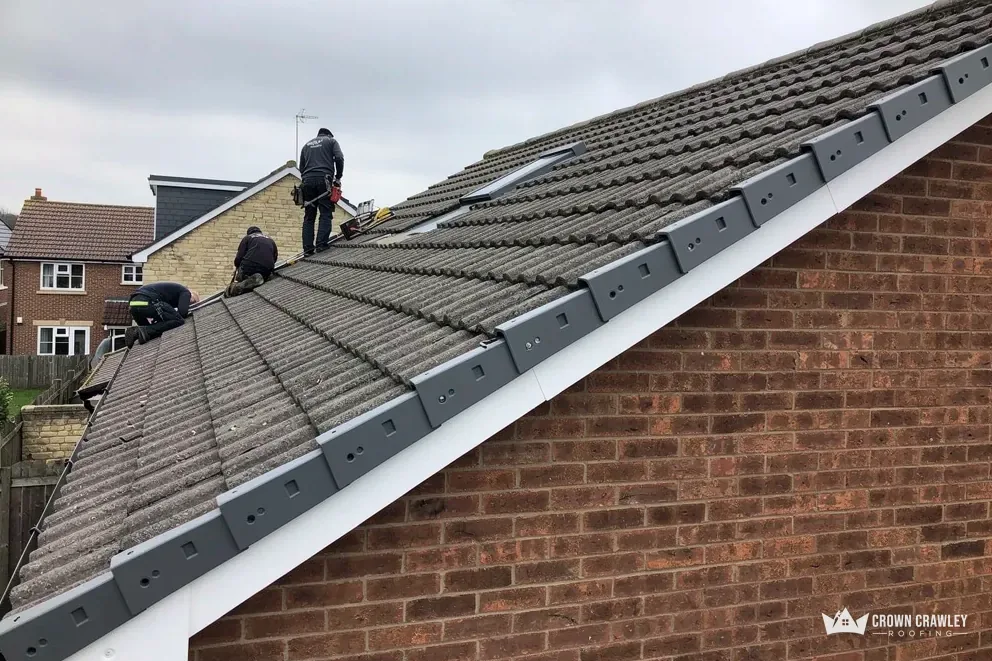 Dry verge trim fitted along a brick gable with roofers above