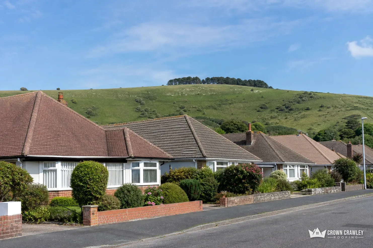 Bungalows on a suburban road beneath rolling downland