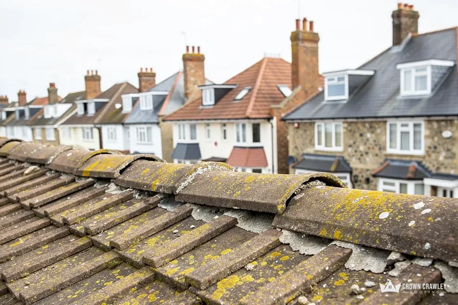 Mossy ridge tiles lifting along the ridge of a terraced roof