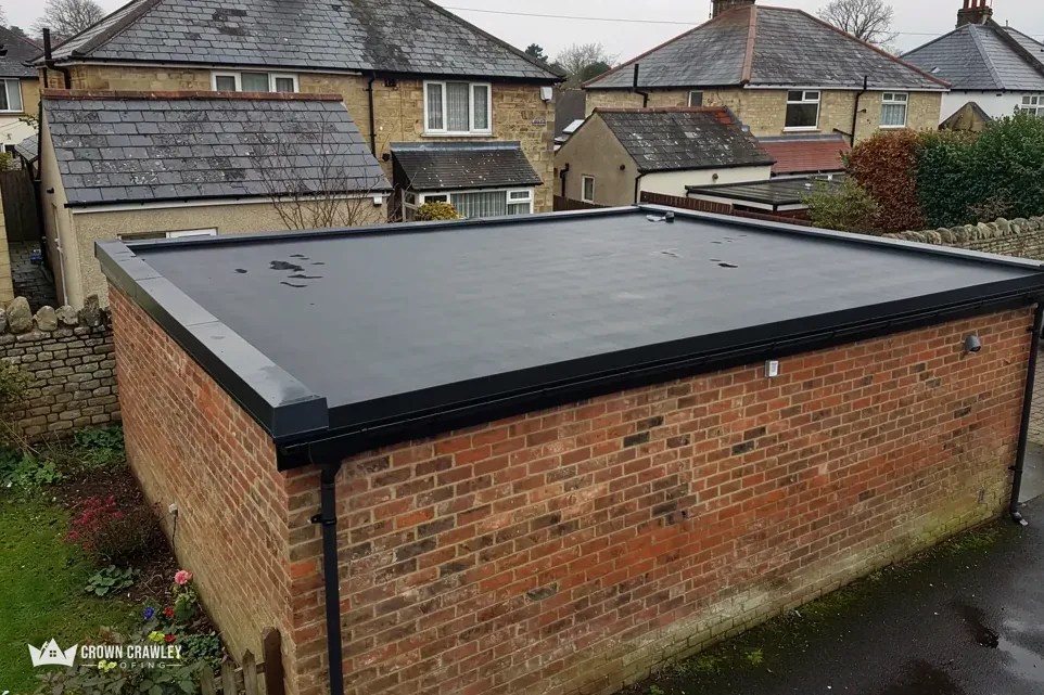 Brick garage topped with a black flat roof and neat edge trim