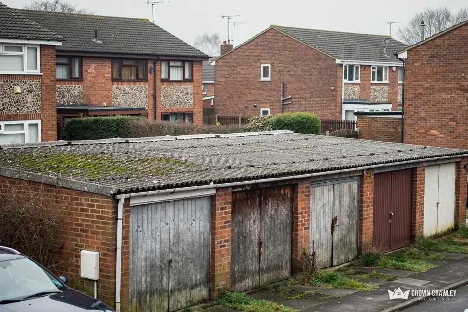 Row of old brick garages with a mossy corrugated roof