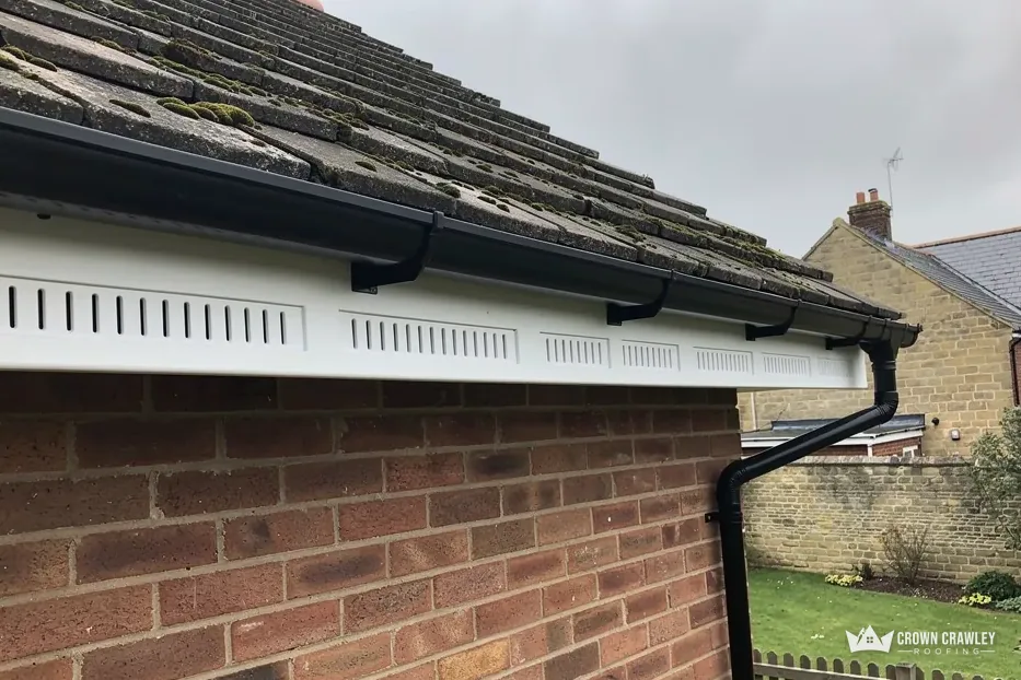 White vented soffit and black guttering on a brick wall