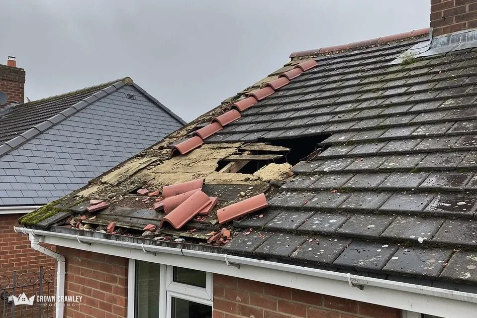 Broken tiles and exposed felt in a slate roof