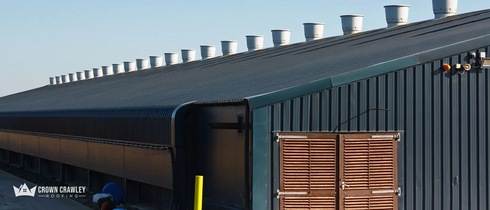 Large dark metal-clad commercial building with vents along the ridge