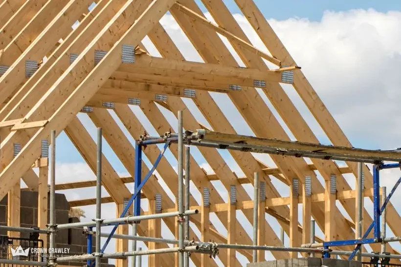 Timber roof trusses on scaffold against a blue sky