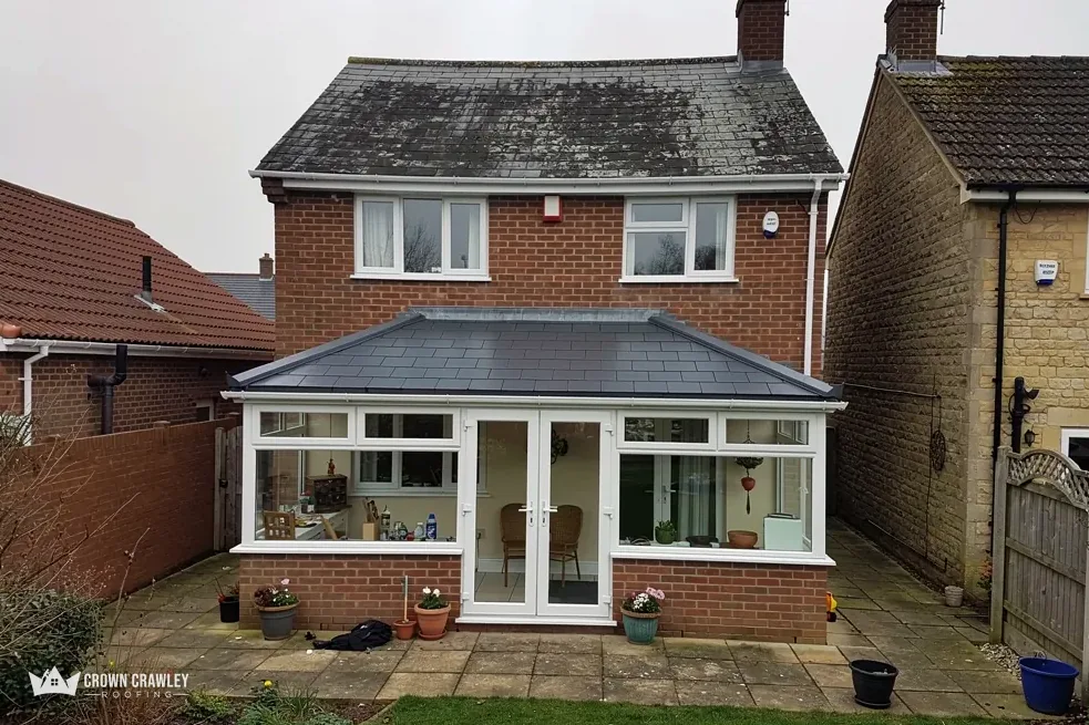 Rear of a brick house with a glazed extension and slate-effect roof