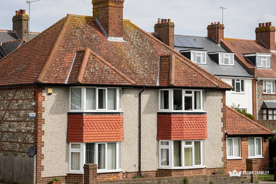 Pebbledash semi-detached house with a red clay tiled roof and bay windows