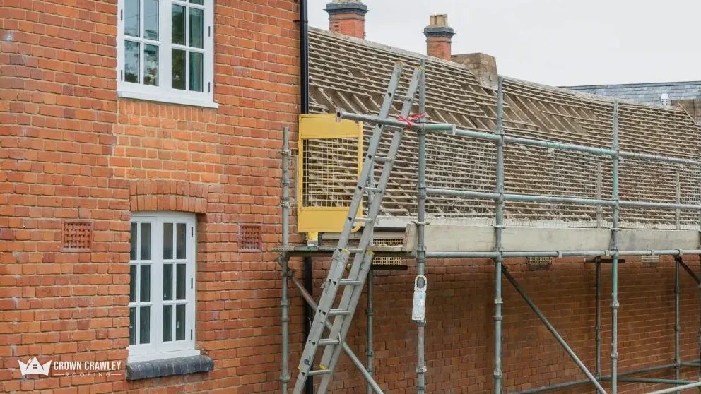 Scaffold and access ladder against a brick terrace with a new tiled roof
