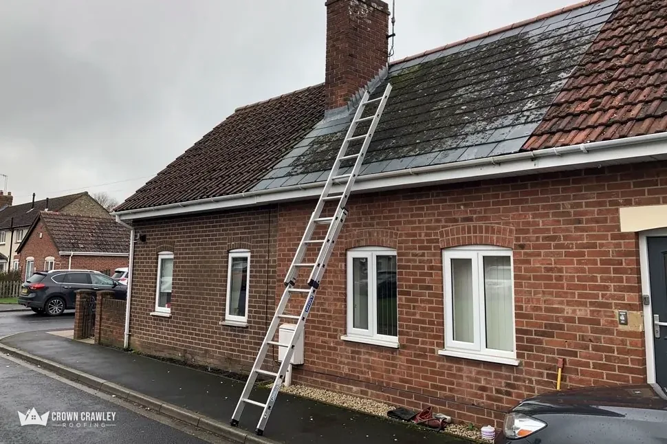 Brick bungalow with a ladder leaning against its tiled roof