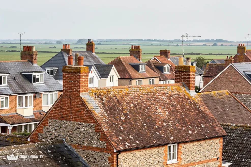 Flint-walled house with a mossy clay tiled roof overlooking fields