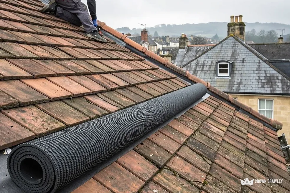 Roll of roofing membrane lying on a clay tiled roof