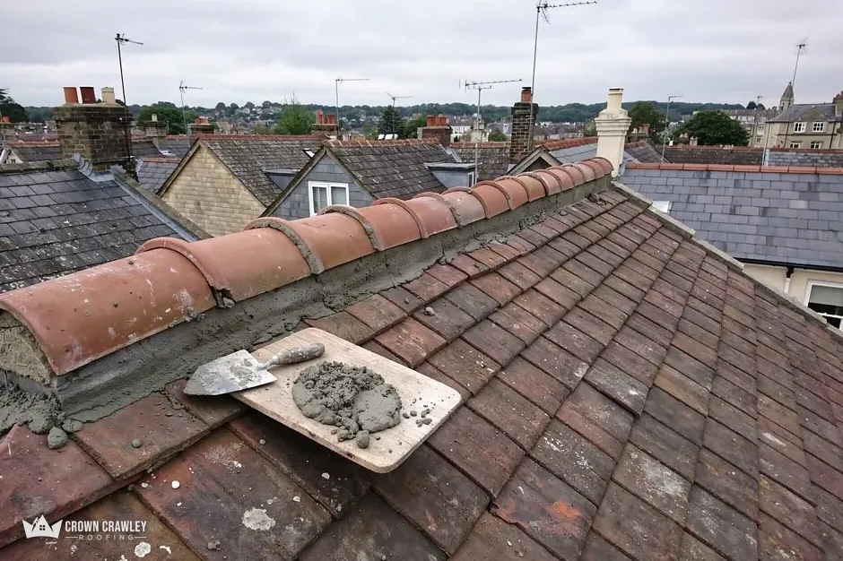 Ridge tile bedded in fresh mortar with a trowel resting on the roof