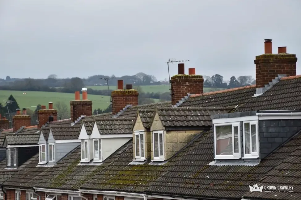 Dormer windows on a weathered tiled roof facing open fields