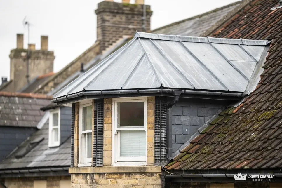 Lead-covered bay roof and chimney stack on a slate and tile roof