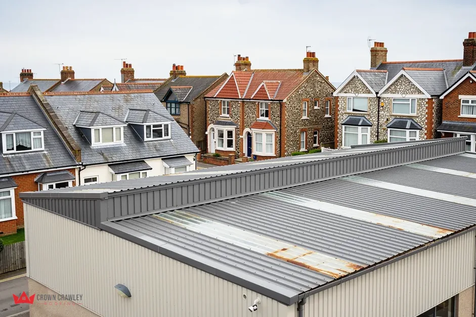 Metal-clad commercial roof with rooflights beside suburban houses