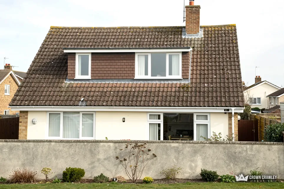 Dormer bungalow with a brown tiled roof and white rendered walls